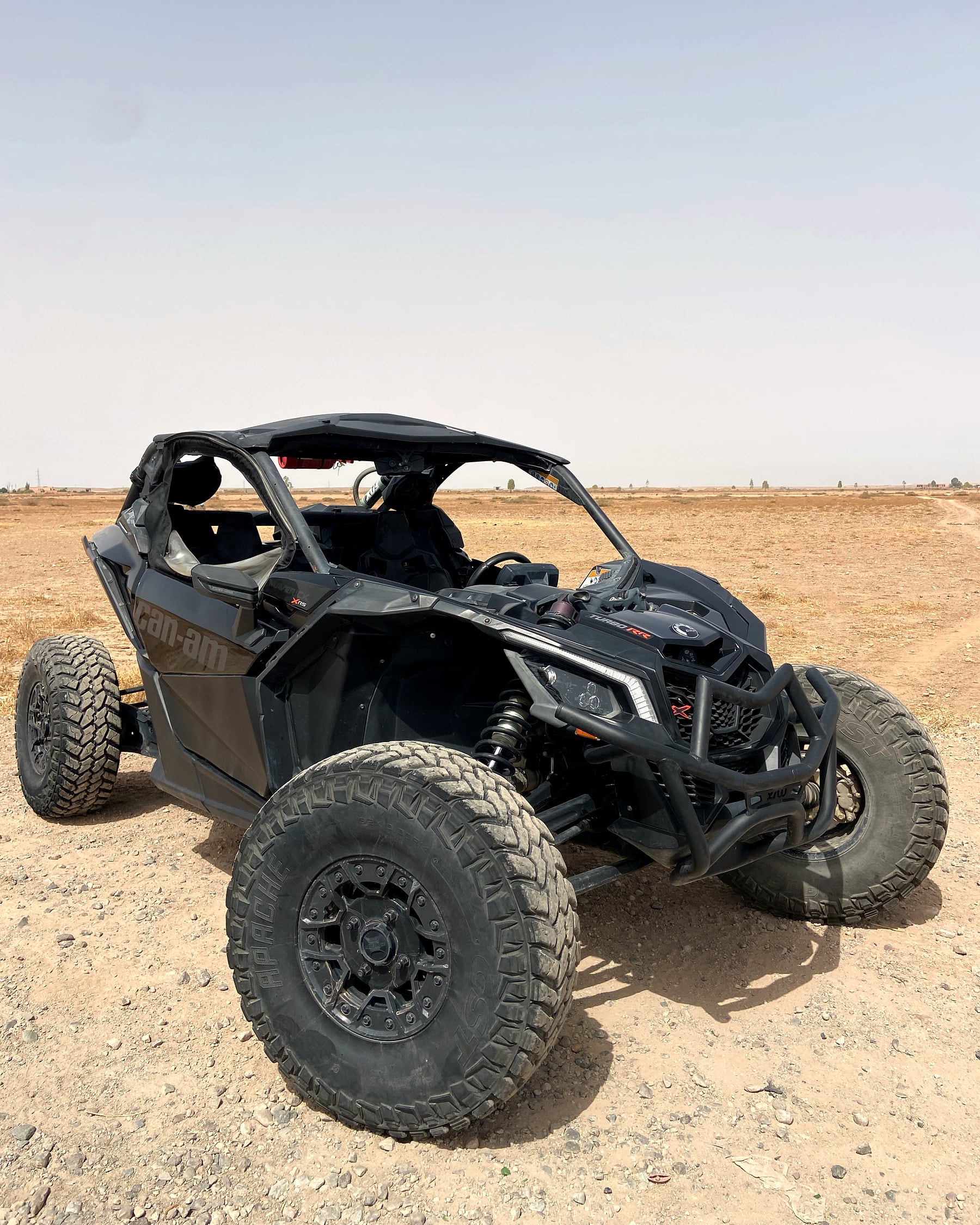 Buggy Can-Am Maverick X3 noir mat, vue trois quarts avant sur terrain rocheux