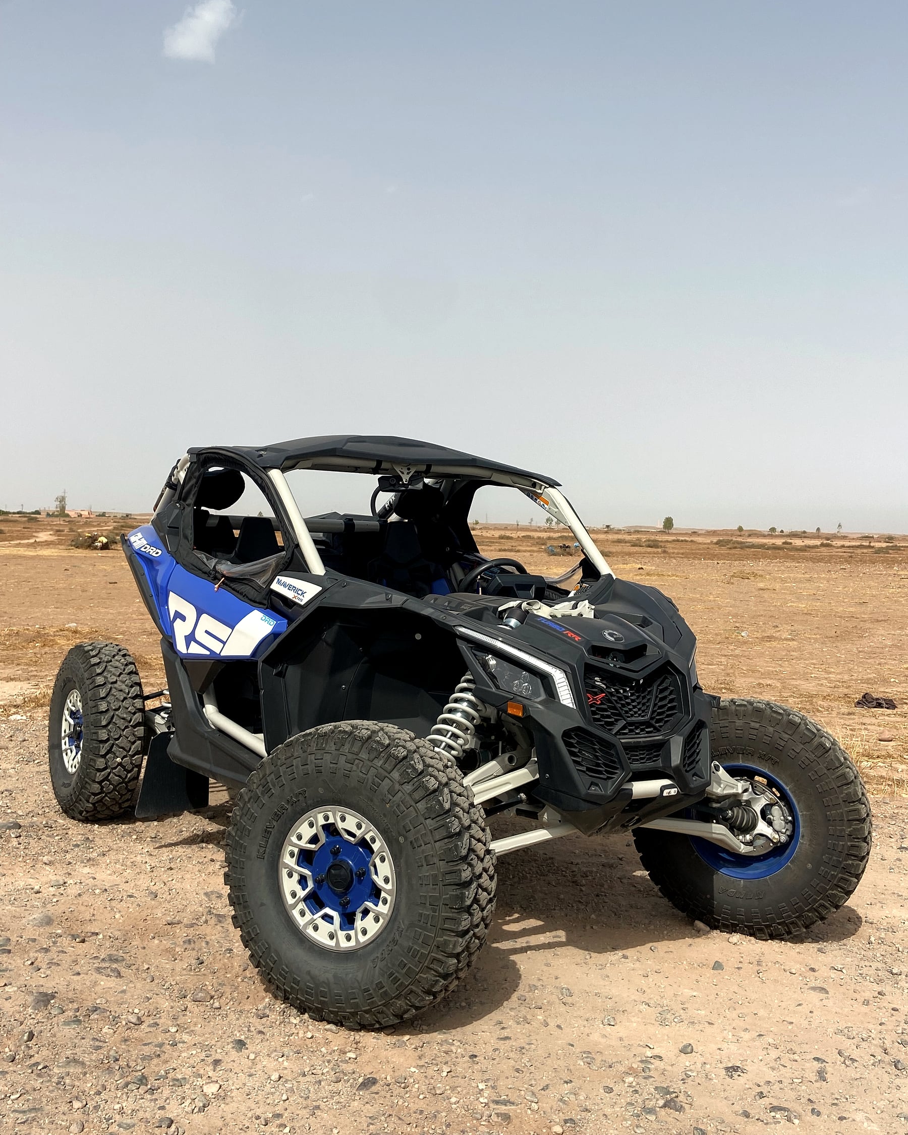 Buggy Can-Am Maverick X3 bleu clair, vue de profil sur terrain rocheux