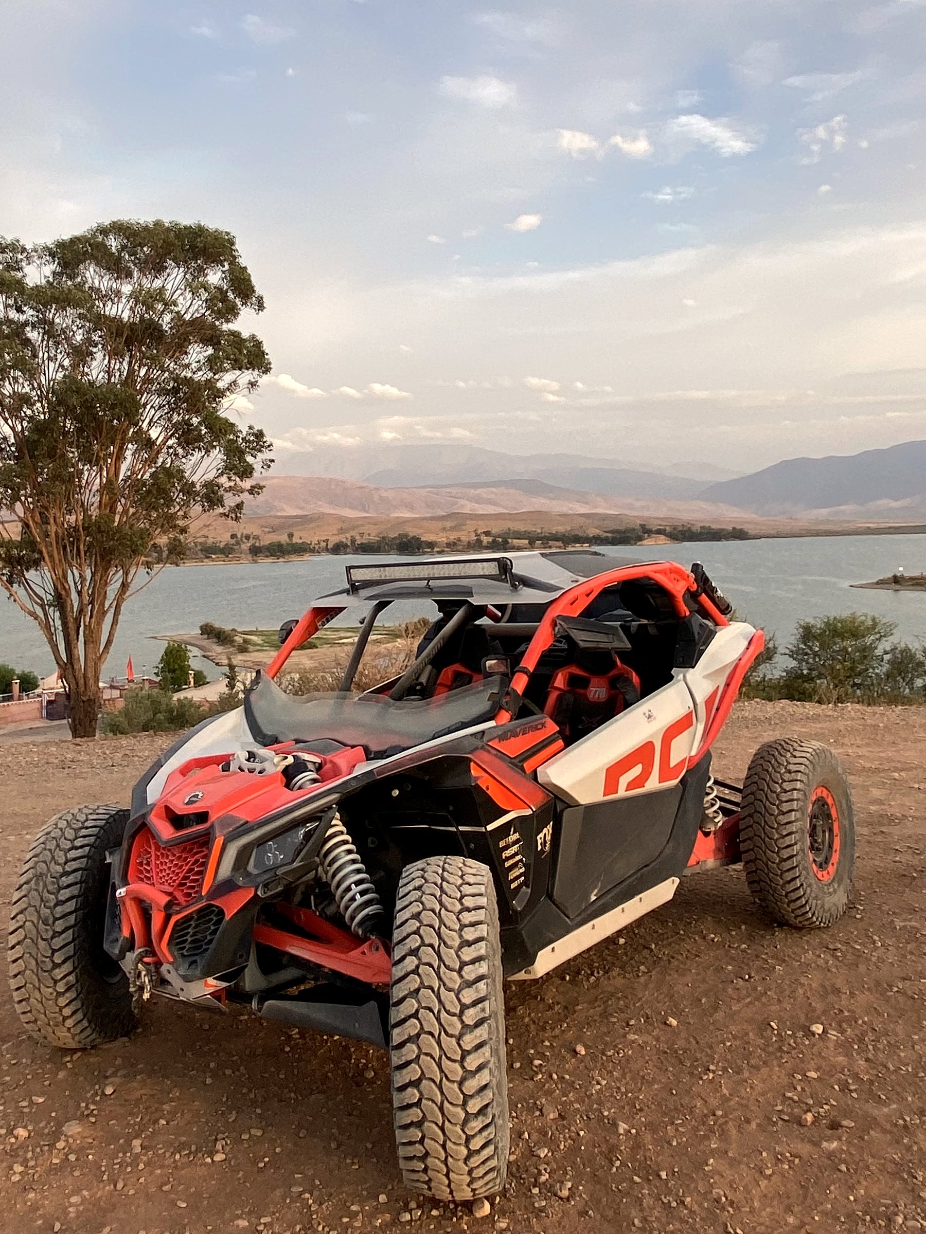 Buggy Can-Am Maverick X3 orange et gris, au bord du lac face aux montagnes