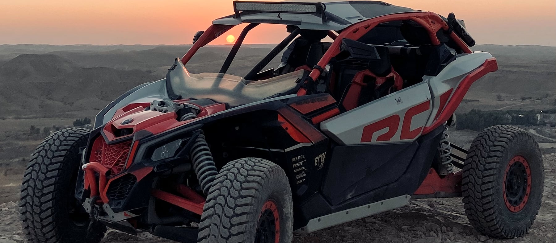 Buggy Can-Am Maverick X3 orange sur une crête au coucher du soleil
