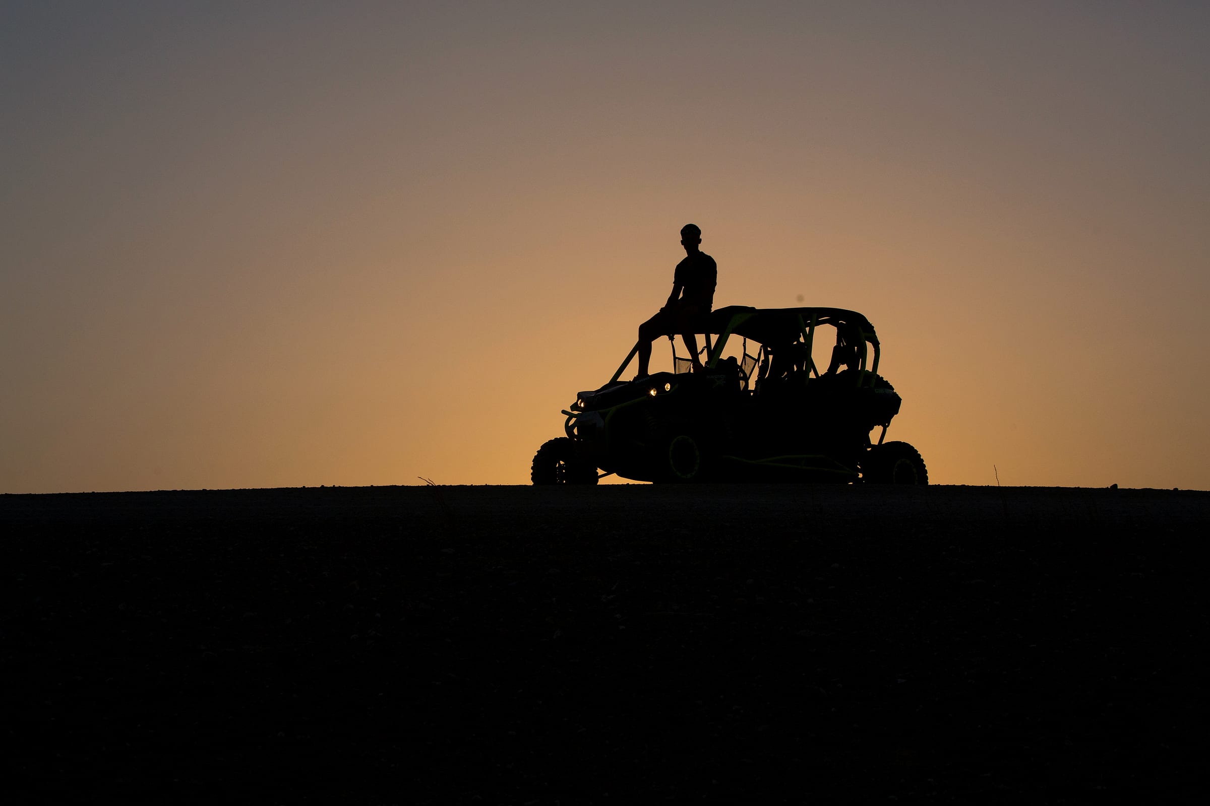 Buggy en silhouette sur une crête de l'Agafay au coucher du soleil