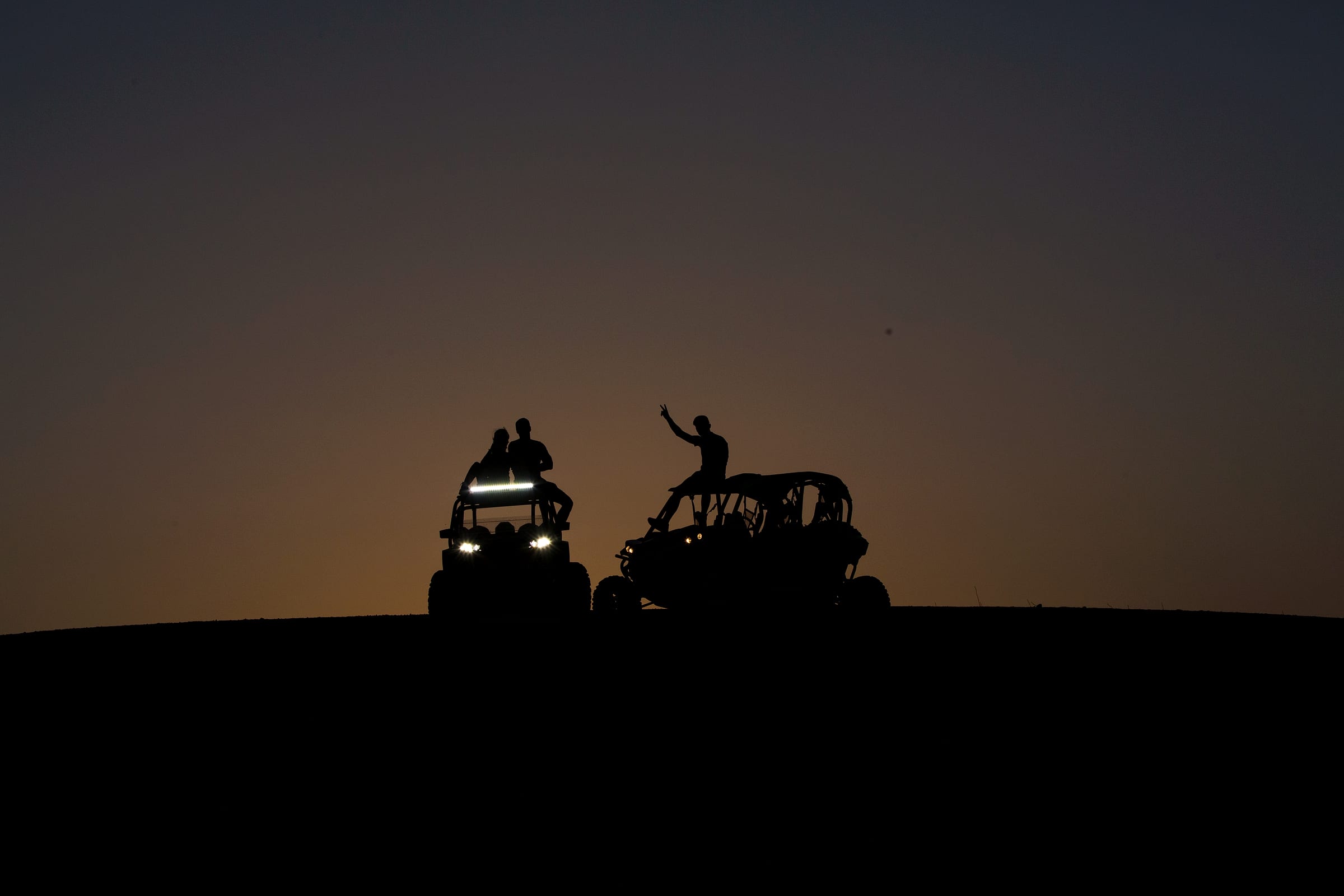Buggy en silhouette sur une crête de l'Agafay au coucher du soleil