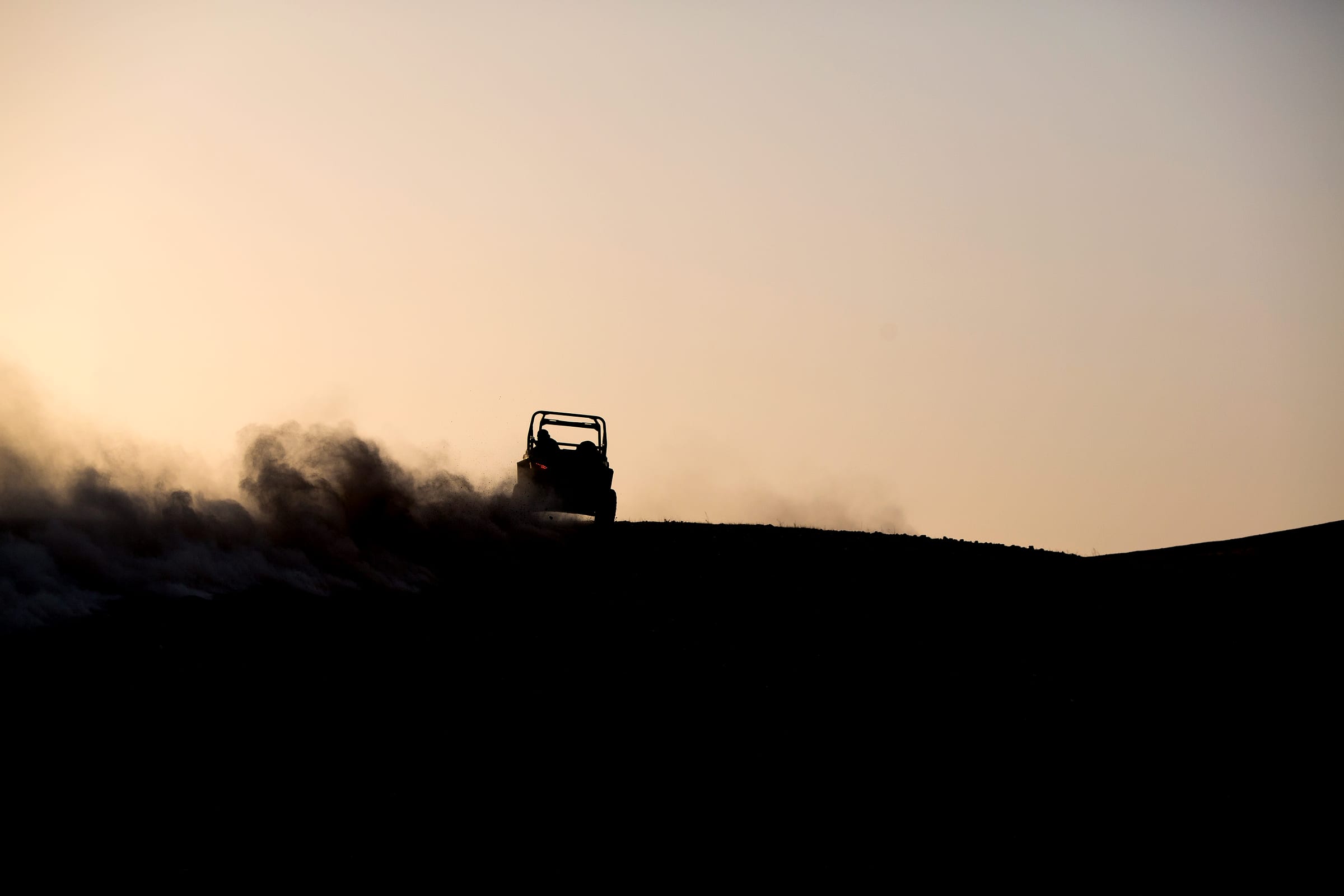 Buggy soulevant un panache de poussière en franchissant une crête rocheuse
