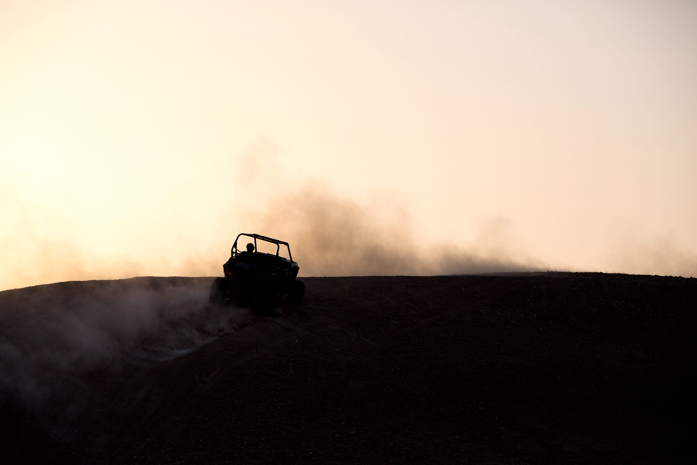 Buggy soulevant un panache de poussière en franchissant une crête rocheuse