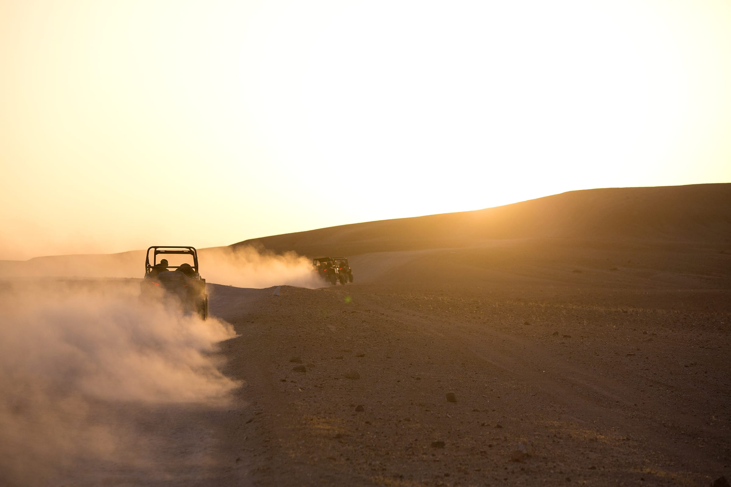 Buggy à contre-jour dans un nuage de poussière doré, lumière rasante