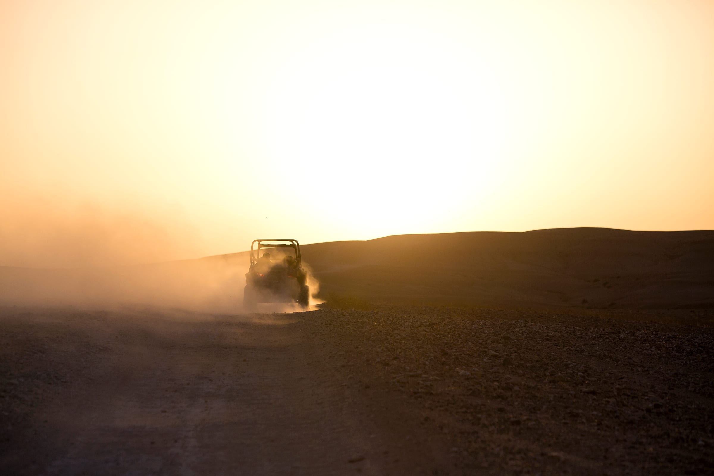 Buggy à contre-jour dans un nuage de poussière doré, lumière rasante