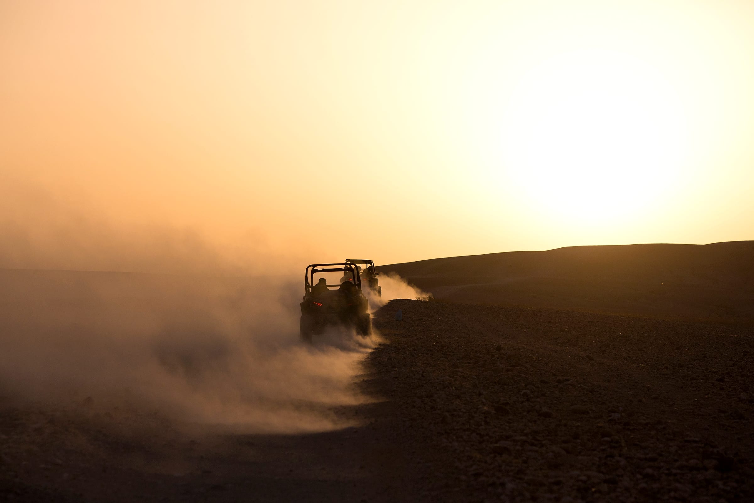 Buggy à contre-jour dans un nuage de poussière doré, lumière rasante