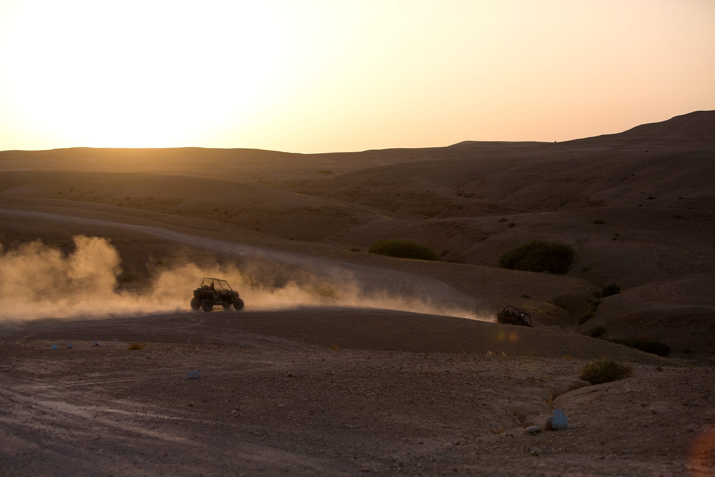 Vaste plateau rocheux de l'Agafay, buggy minuscule au loin sur la piste