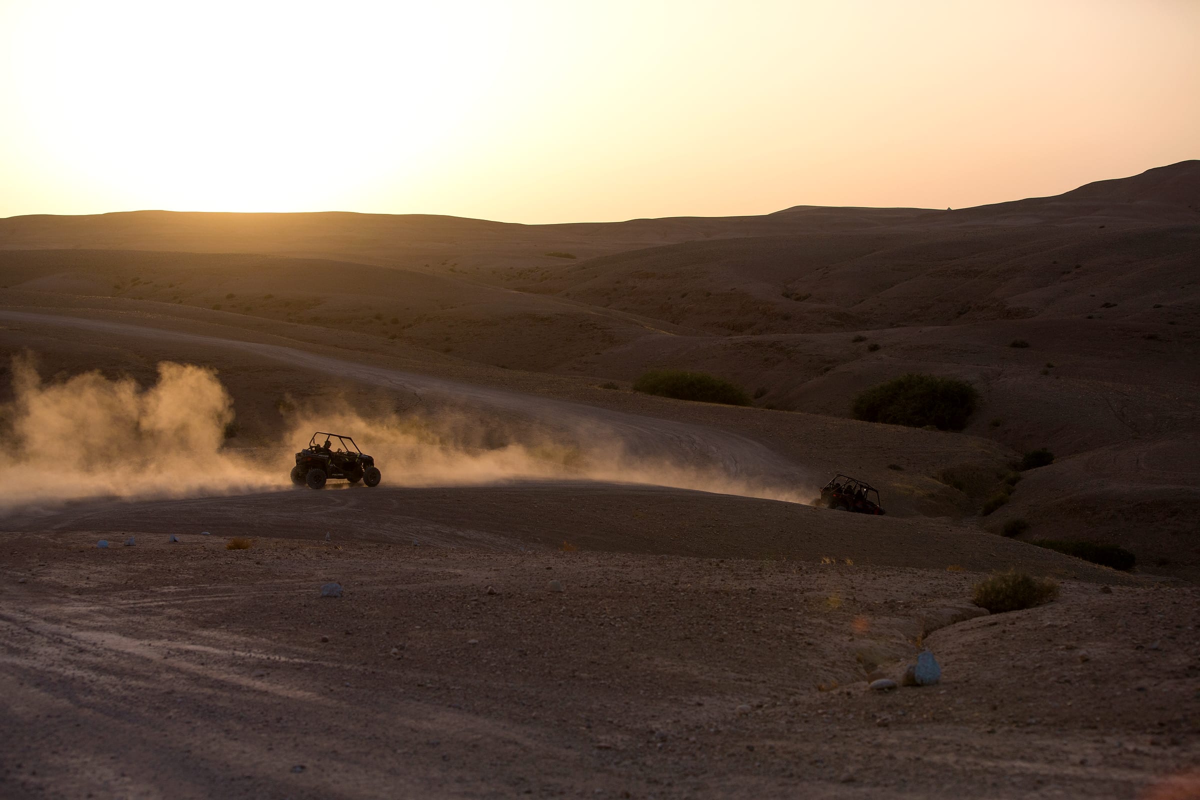 Vaste plateau rocheux de l'Agafay, buggy minuscule au loin sur la piste