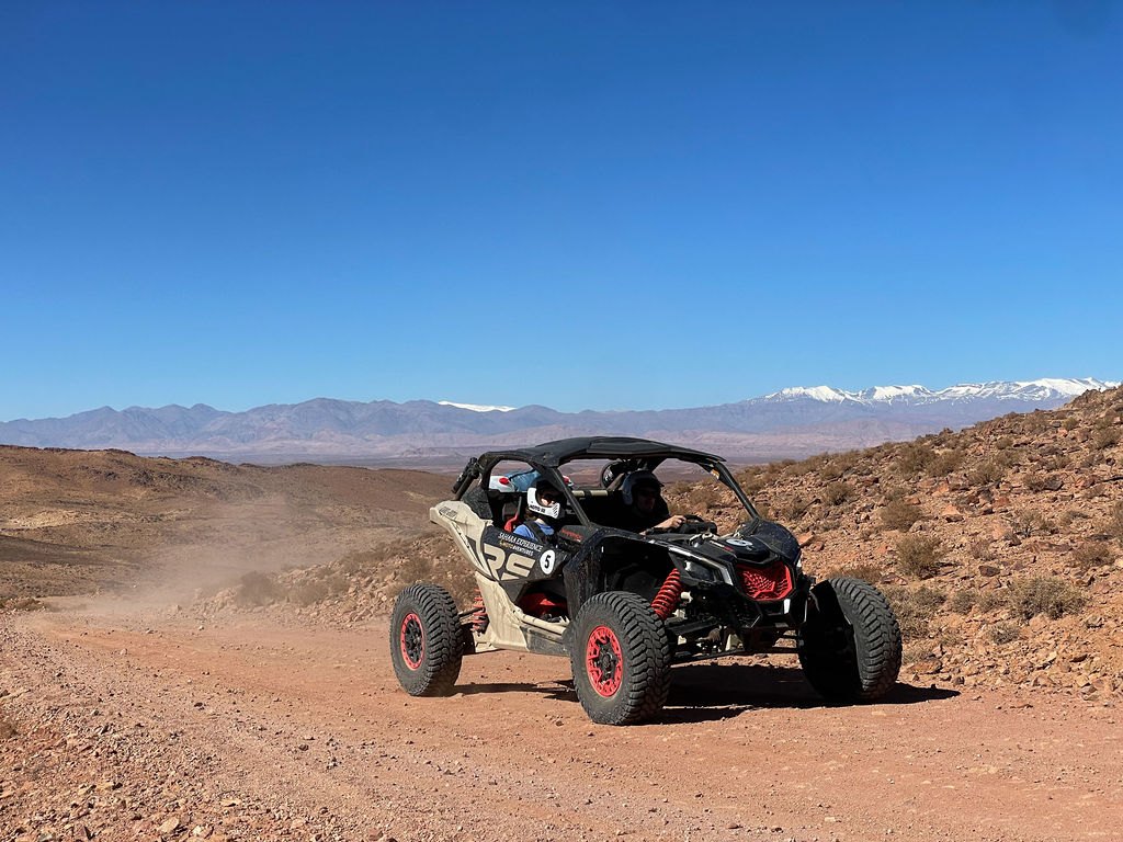 Buggy Can-Am sur une piste face aux sommets enneigés du Haut Atlas