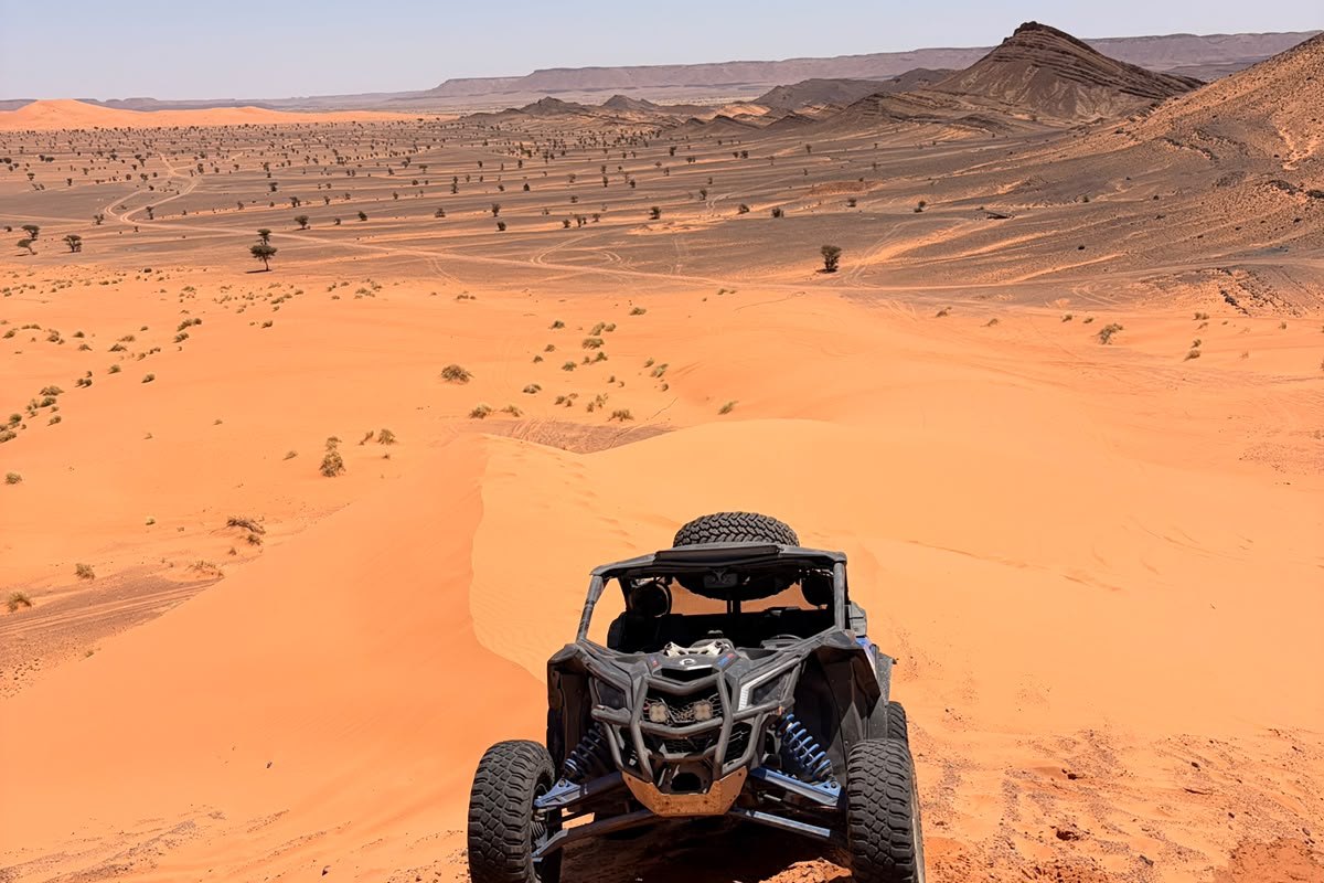 Pilote près de son buggy Can-Am au milieu des dunes